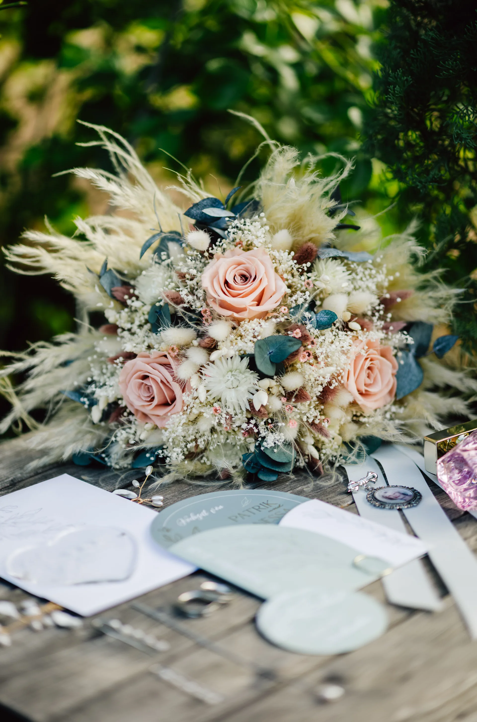 Rosafarbene Blumen und Gräser auf einem gedeckten Holztisch