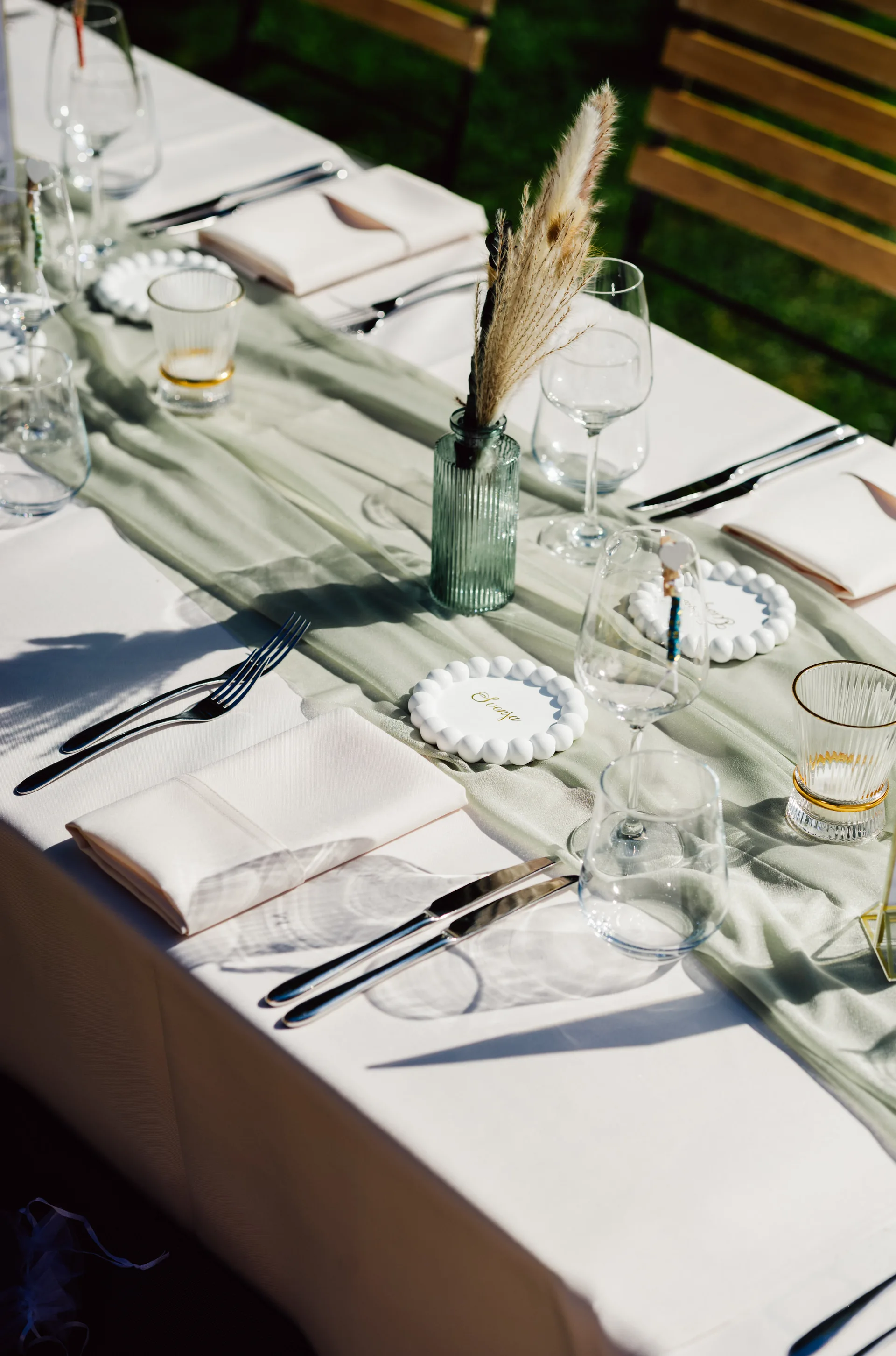 Festlich gedeckte Tafel mit weißen Tellern, Gläsern und schmalen Vasen